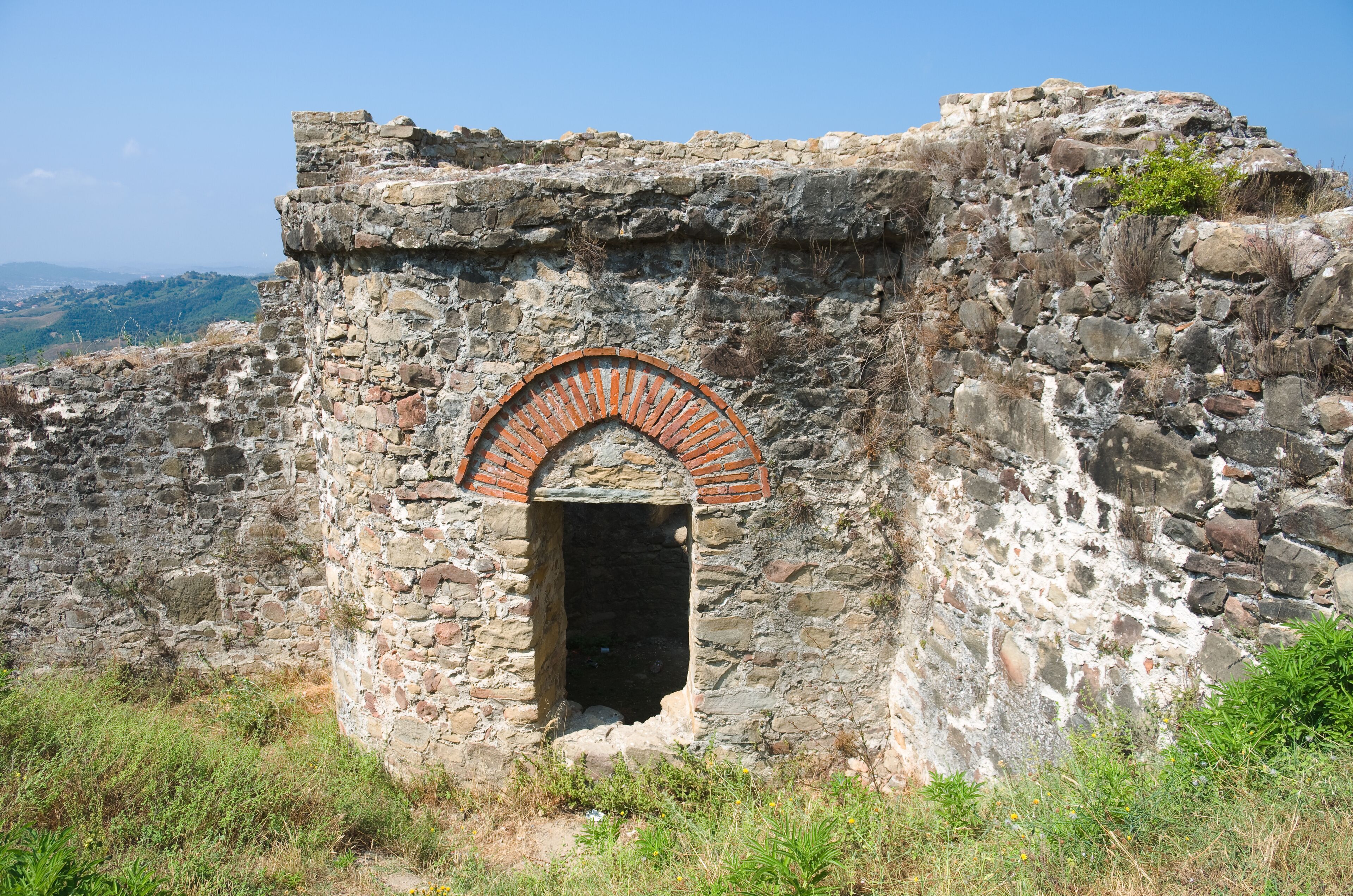 An ancient stone structure with a brick archway and a small opening.