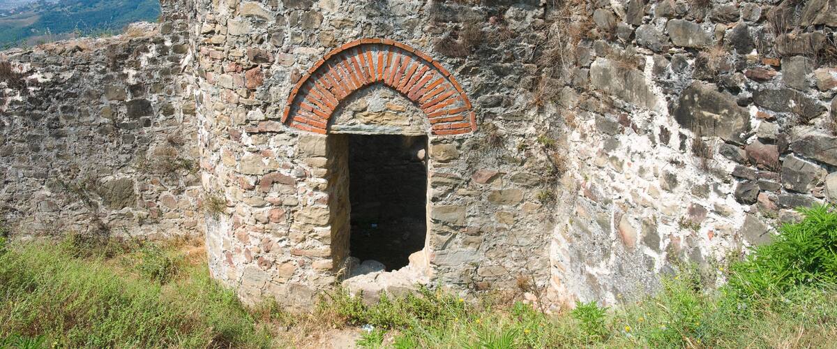 An ancient stone structure with a brick archway and a small opening.