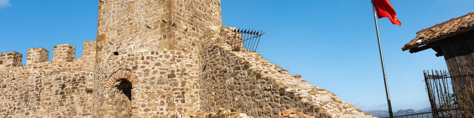 Clock Tower of Preze Castle, Tirana with albanian flag on blue sky background