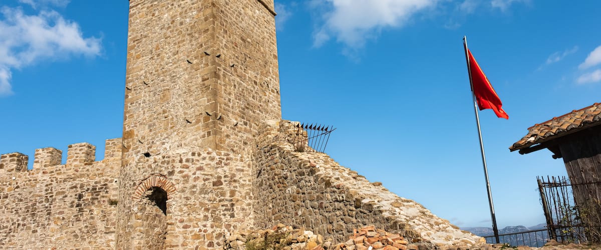 Clock Tower of Preze Castle, Tirana with albanian flag on blue sky background