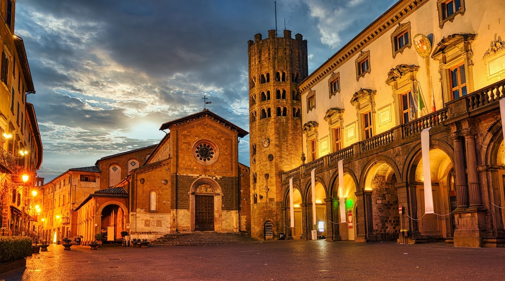 A historic square with a church, a castle, and ornate buildings under a twilight sky.