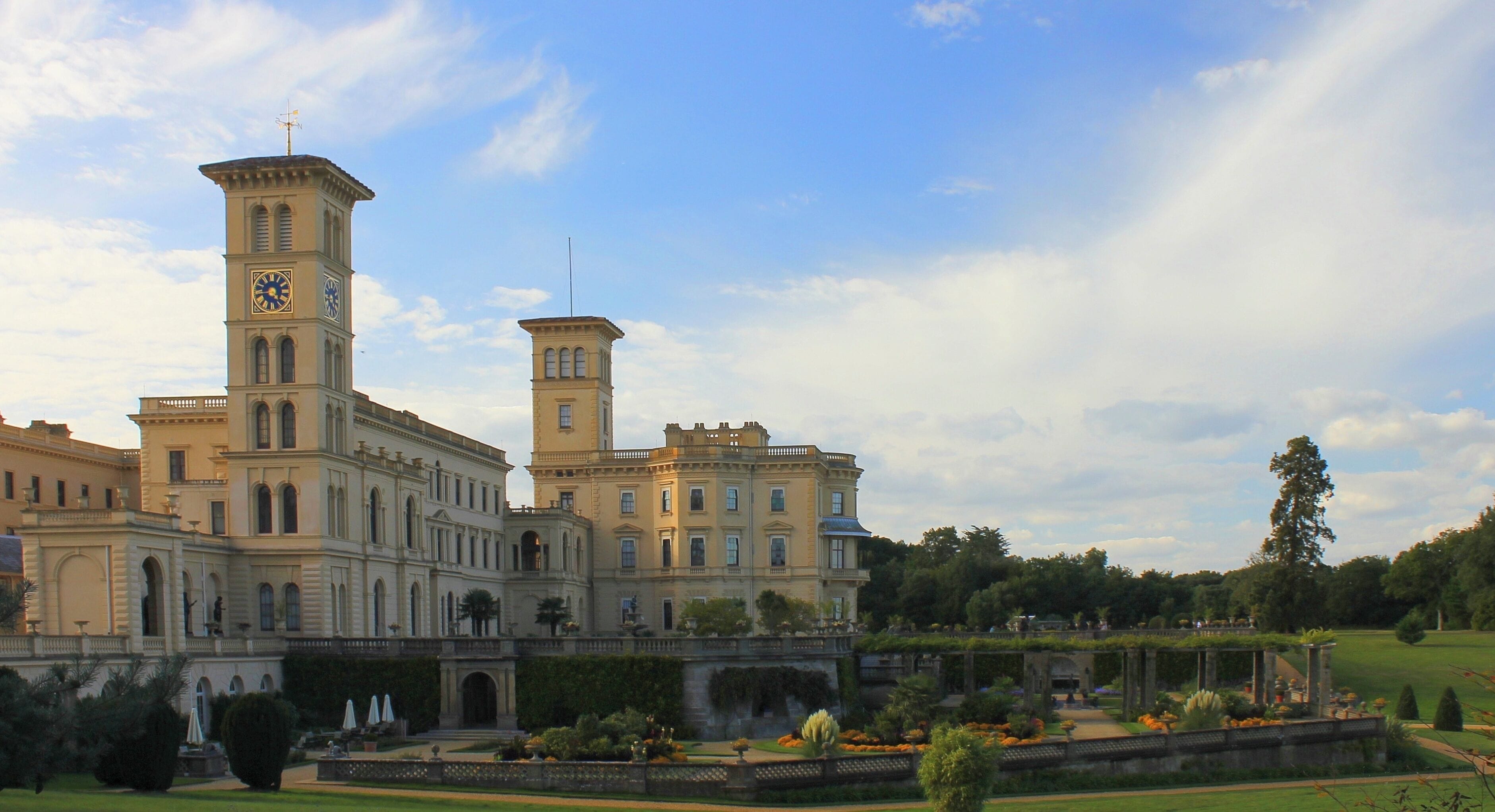 A large historic building with two towers, one with a clock.