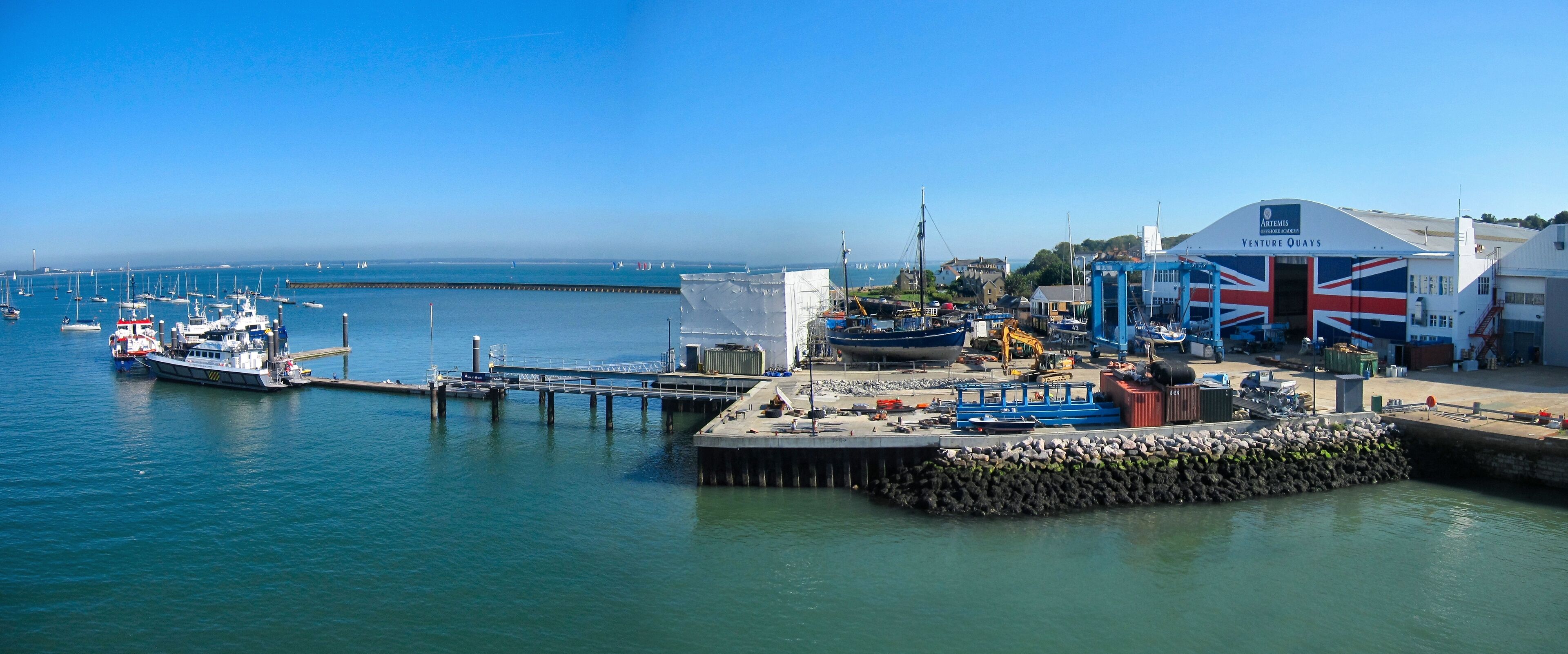 A harbor with boats, a pier, and a building with a Union Jack flag.