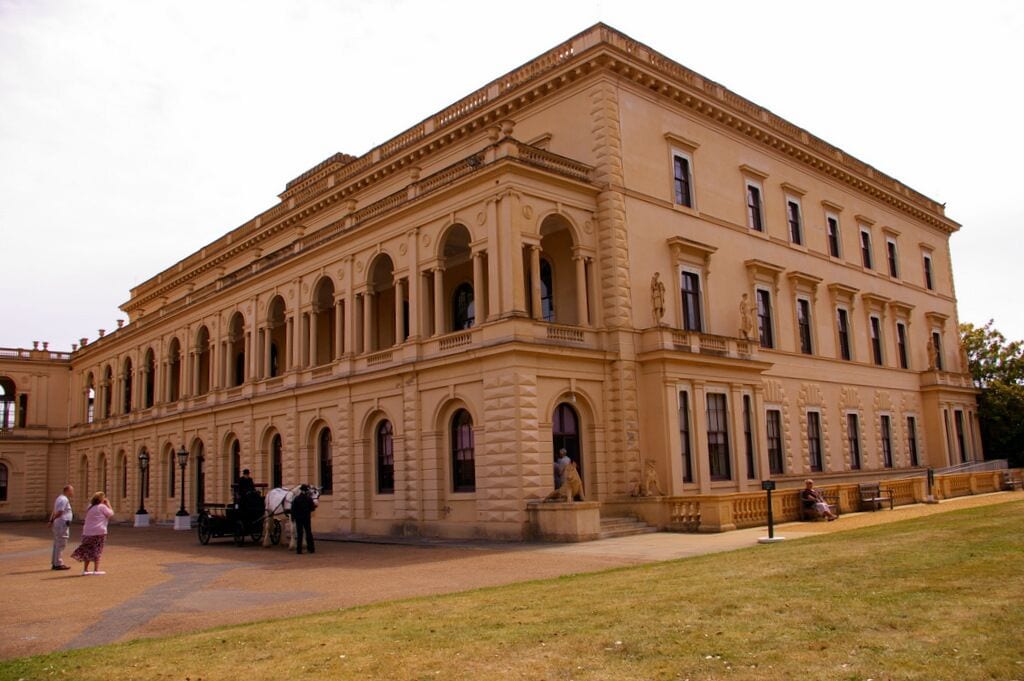 A large, classical building with arched windows and columns, surrounded by a grassy area.
