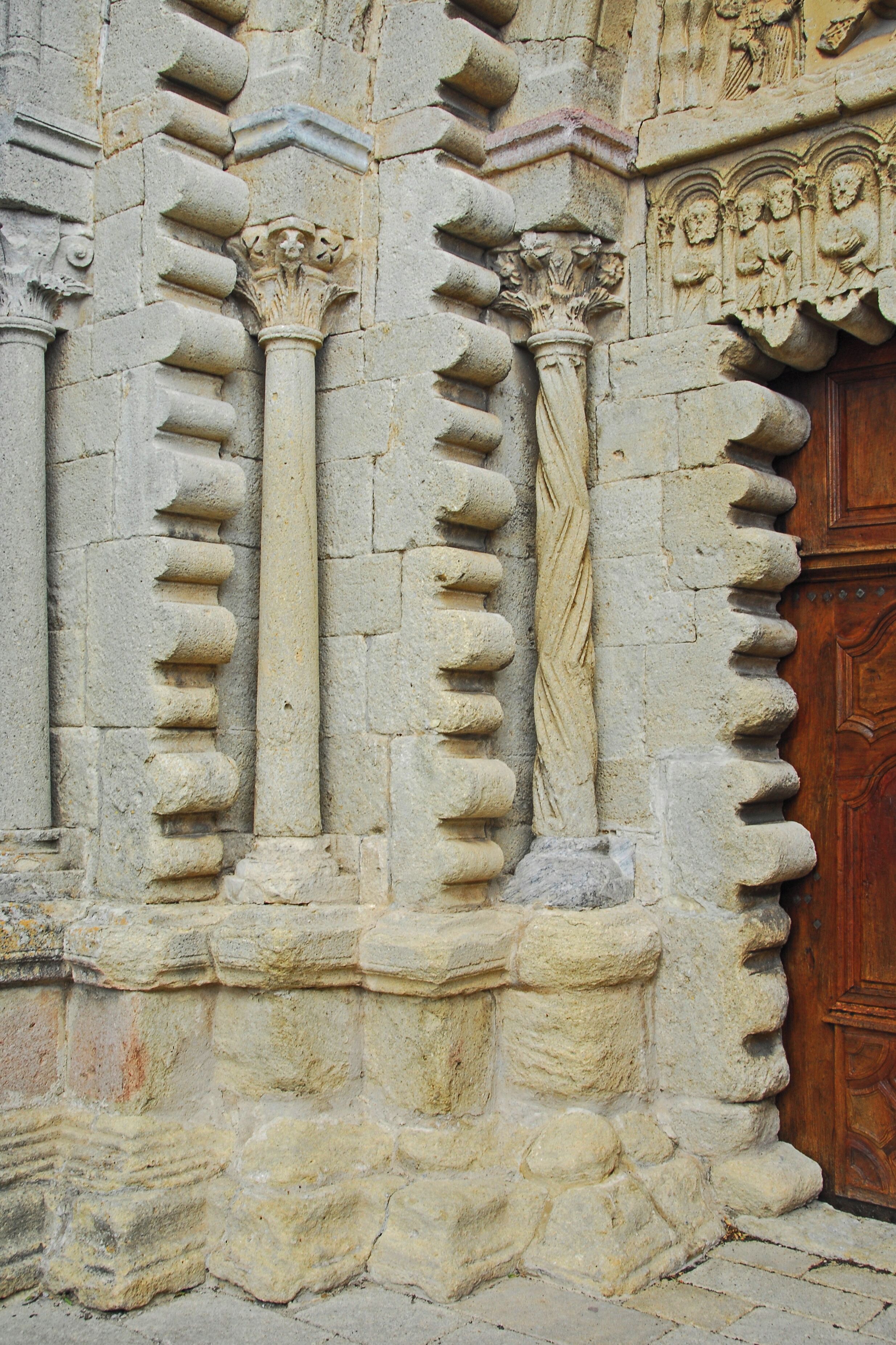 A stone building with carved columns and a wooden door.