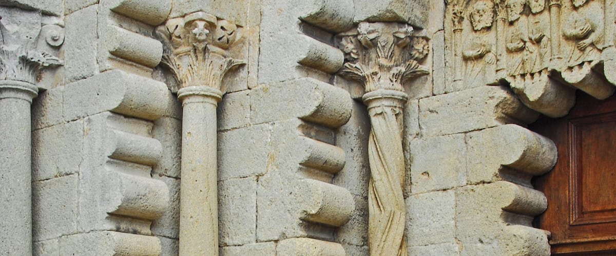 A stone building with carved columns and a wooden door.