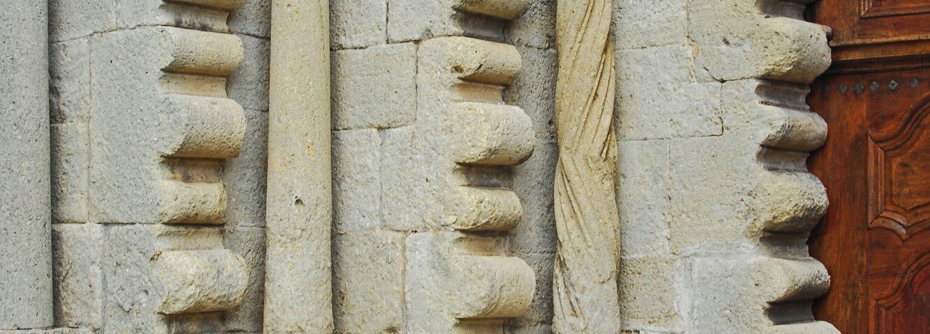 A stone building with carved columns and a wooden door.