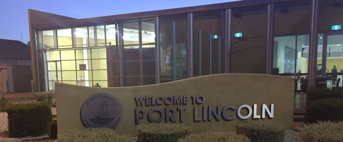 A welcome sign for Port Lincoln with a modern building in the background.