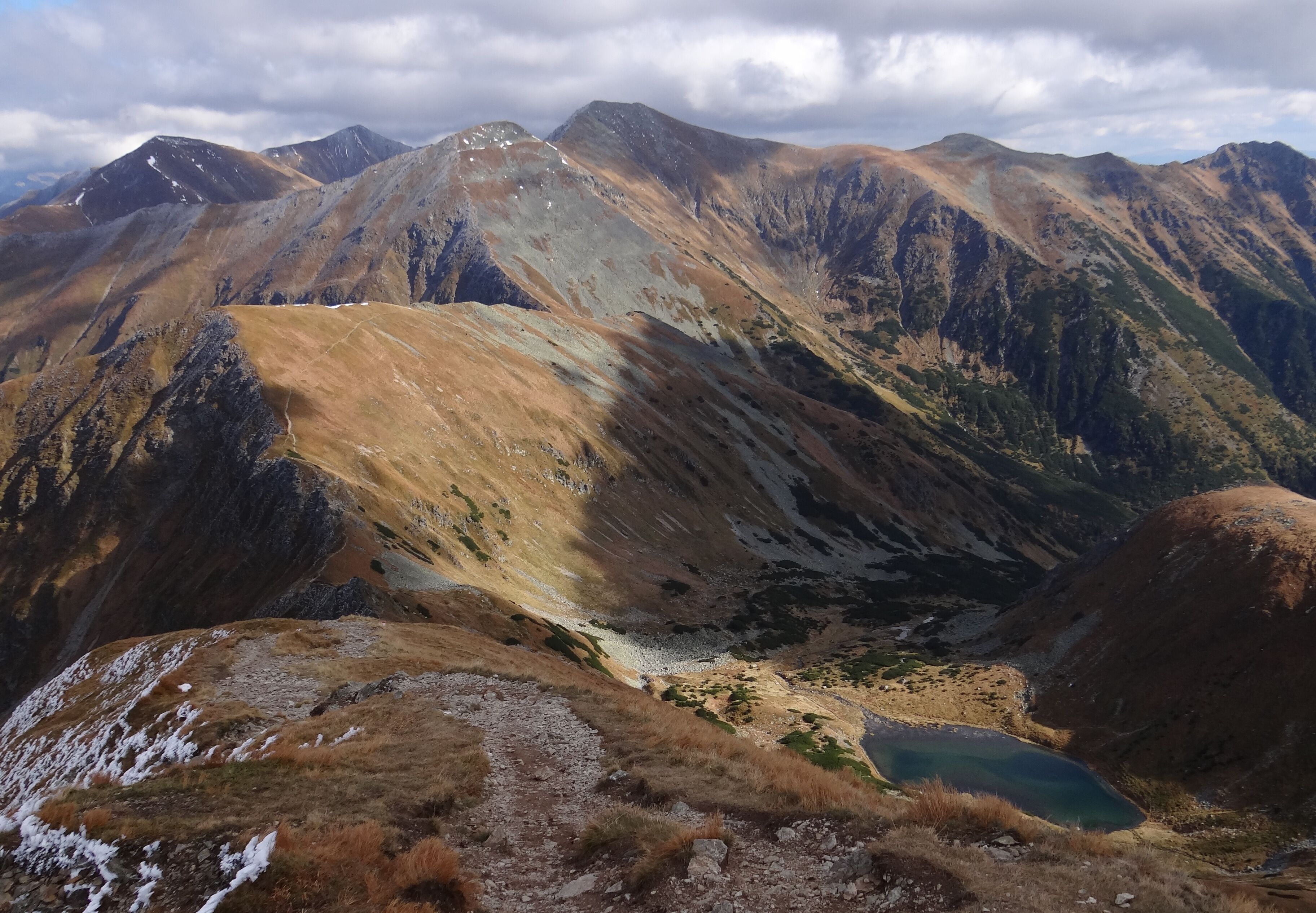 A mountainous landscape with a valley and a small lake.