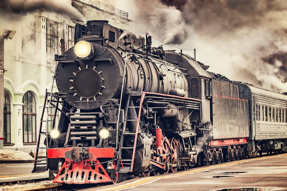 A steam locomotive with a large headlight and steam emitting from its chimney.