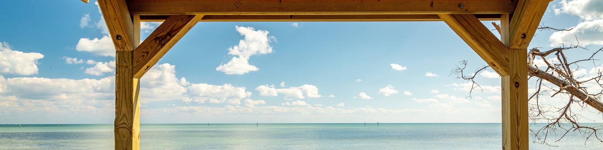A wooden deck with benches overlooking a clear blue sea.