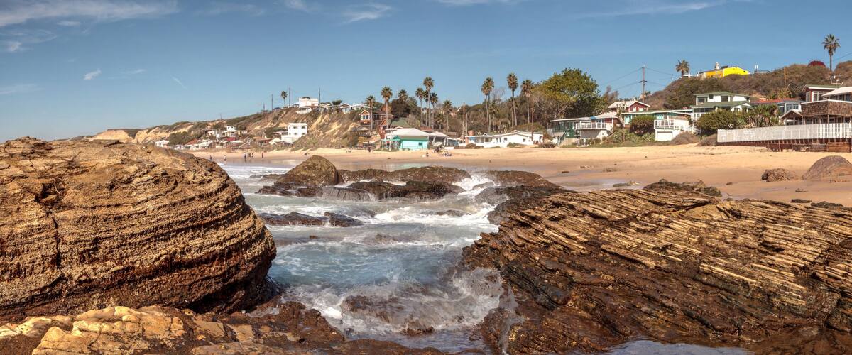 Rocky shore with Beach cottages lining Crystal Cove State Park beach