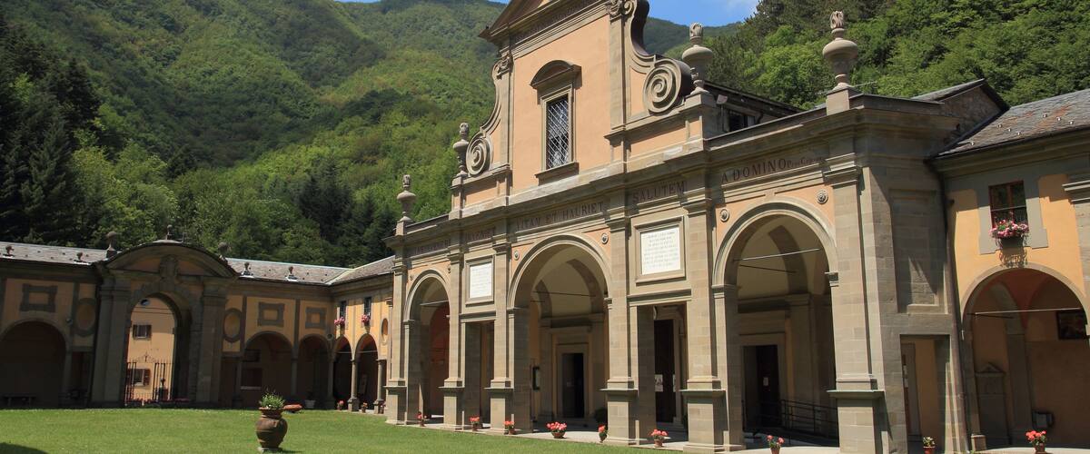 A historic building with arched walkways and a lush green courtyard.