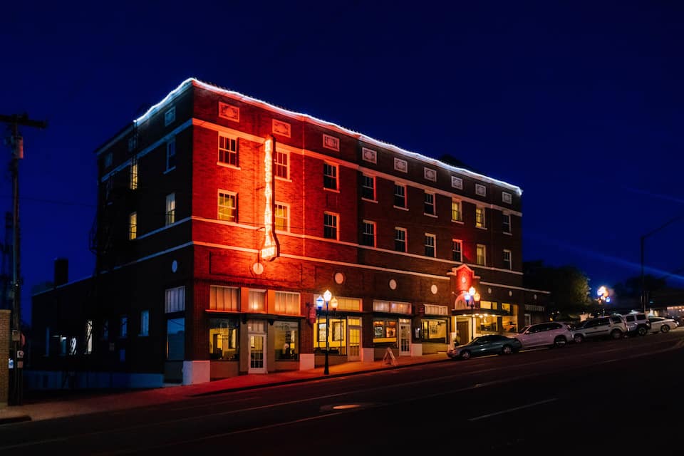 A multi-story building with illuminated signage and a red brick facade at night.