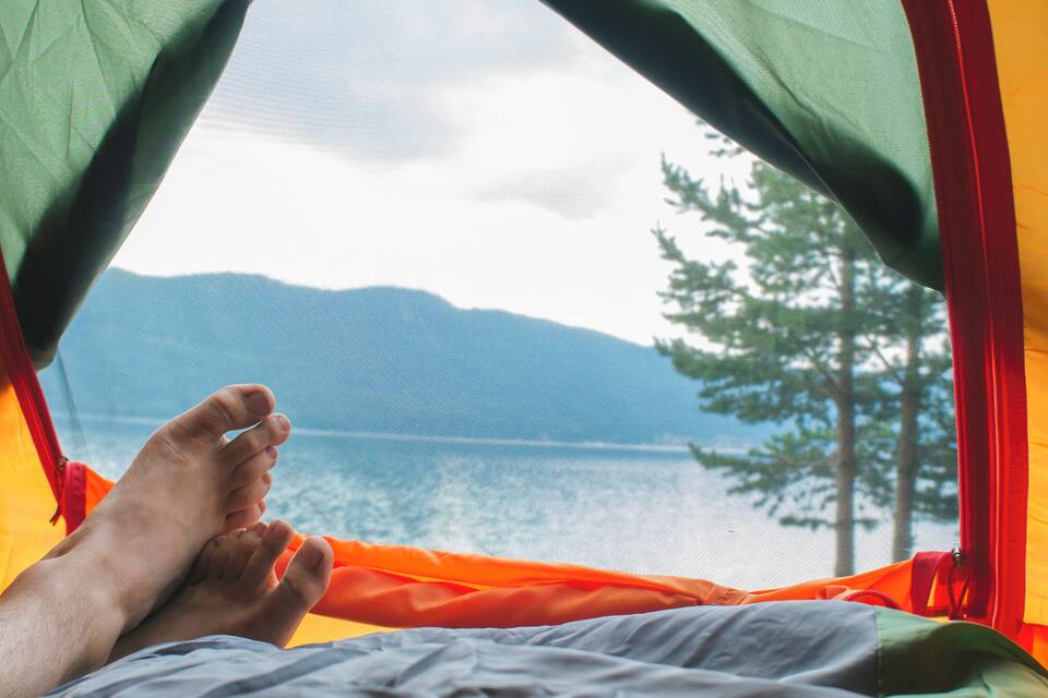 A tent with a view of a lake and mountains.