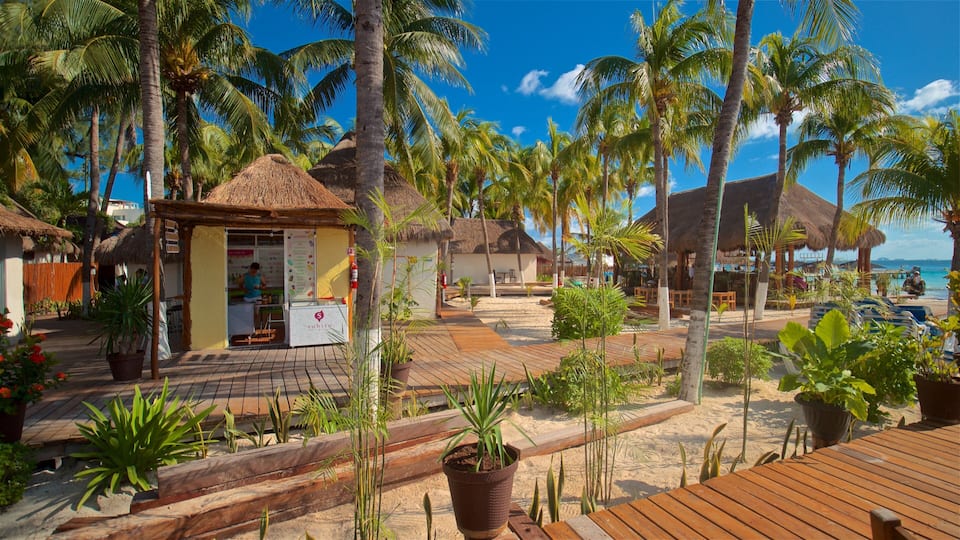 A tropical resort with thatched-roof huts, palm trees, and a wooden deck.
