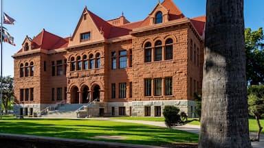 A large, historic red-brick building with a red-tiled roof, arched windows, and a central entrance with steps.