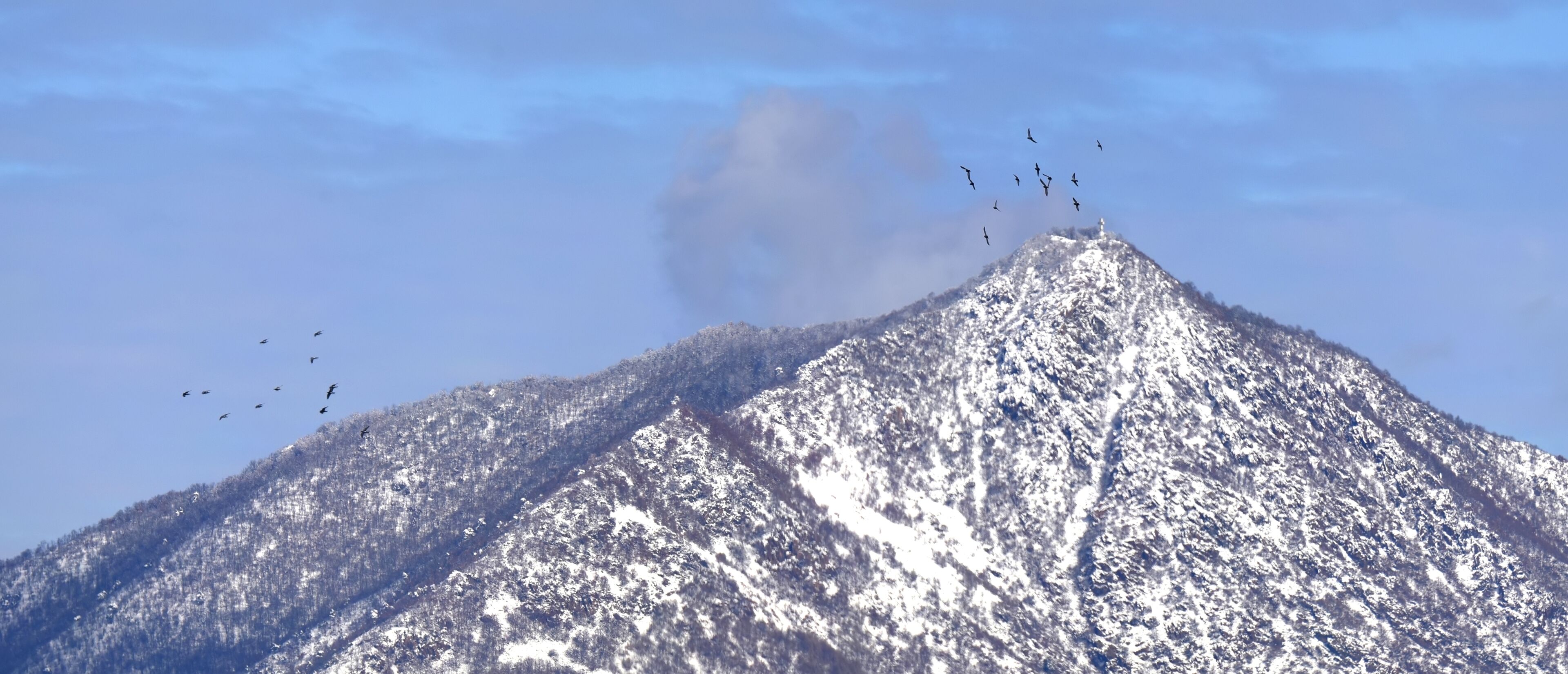 A snow-covered mountain with a peak emitting smoke.