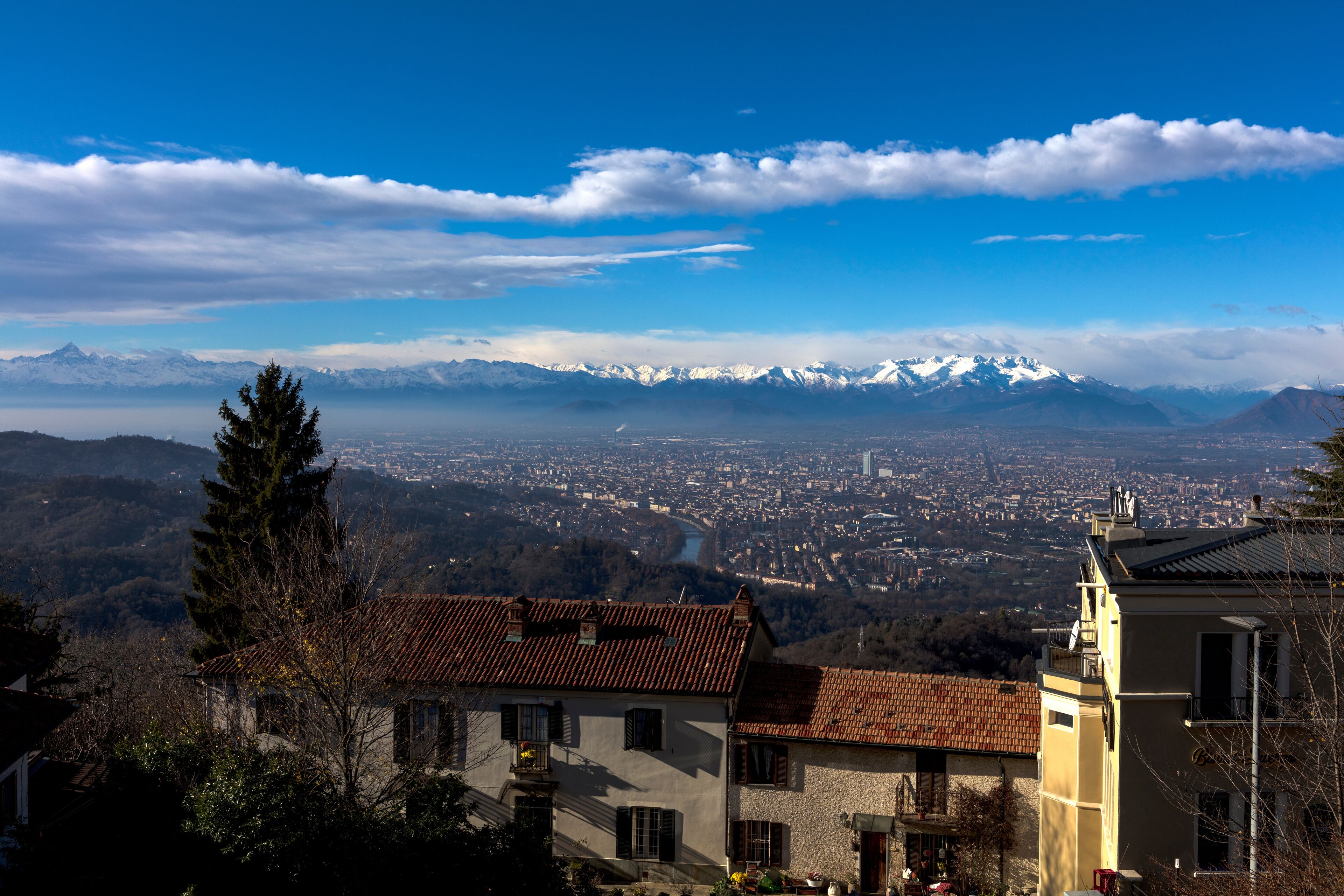 A mountain range with snow-capped peaks, a town below, and a clear blue sky.