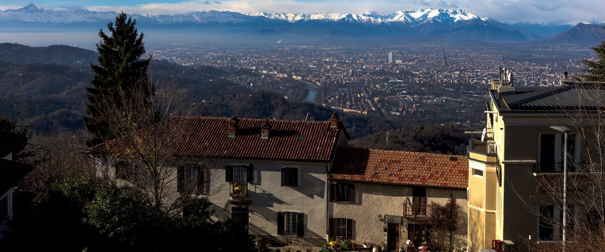 A mountain range with snow-capped peaks, a town below, and a clear blue sky.