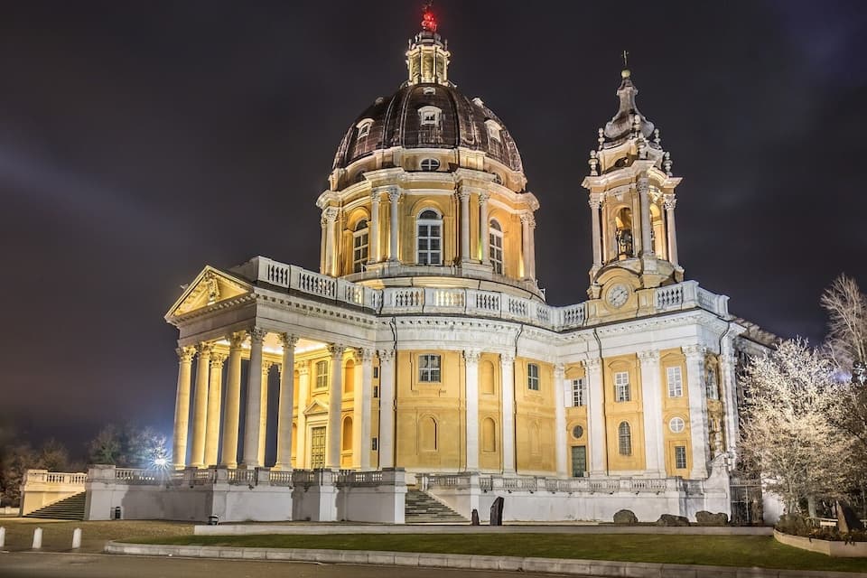 A grand, illuminated building with a large dome and two towers at night.