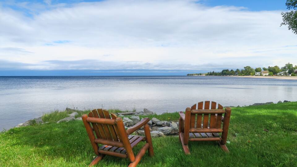 Peaceful view of two wooden chairs facing the lac St Jean, in Quebec