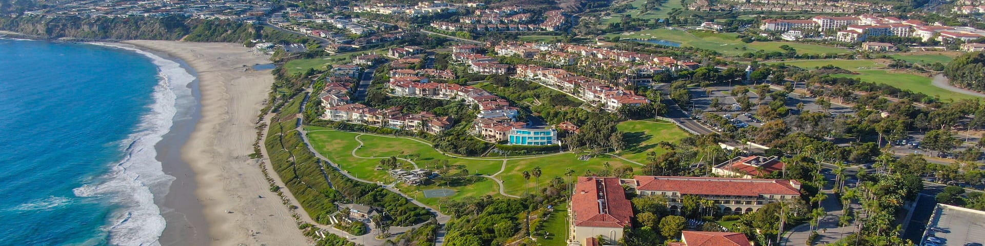 A coastal resort with a beachfront, a golf course, and a large pool area.