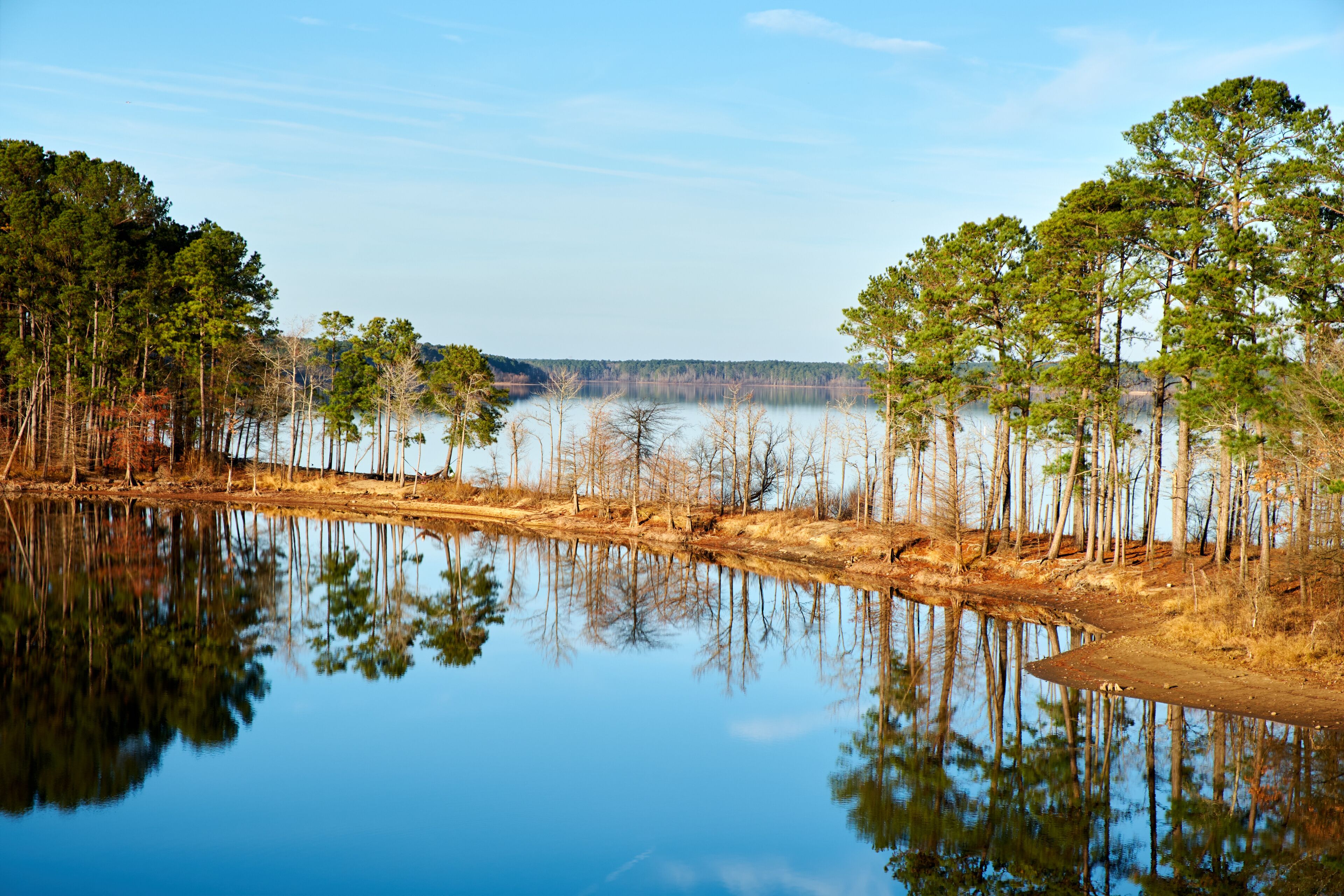 HDR Lakes with trees reflection on smooth water on a sunny winters day. Thin strip of land separates 2 lakes. The smooth water creates a perfect mirror image of the trees in the reflection.
