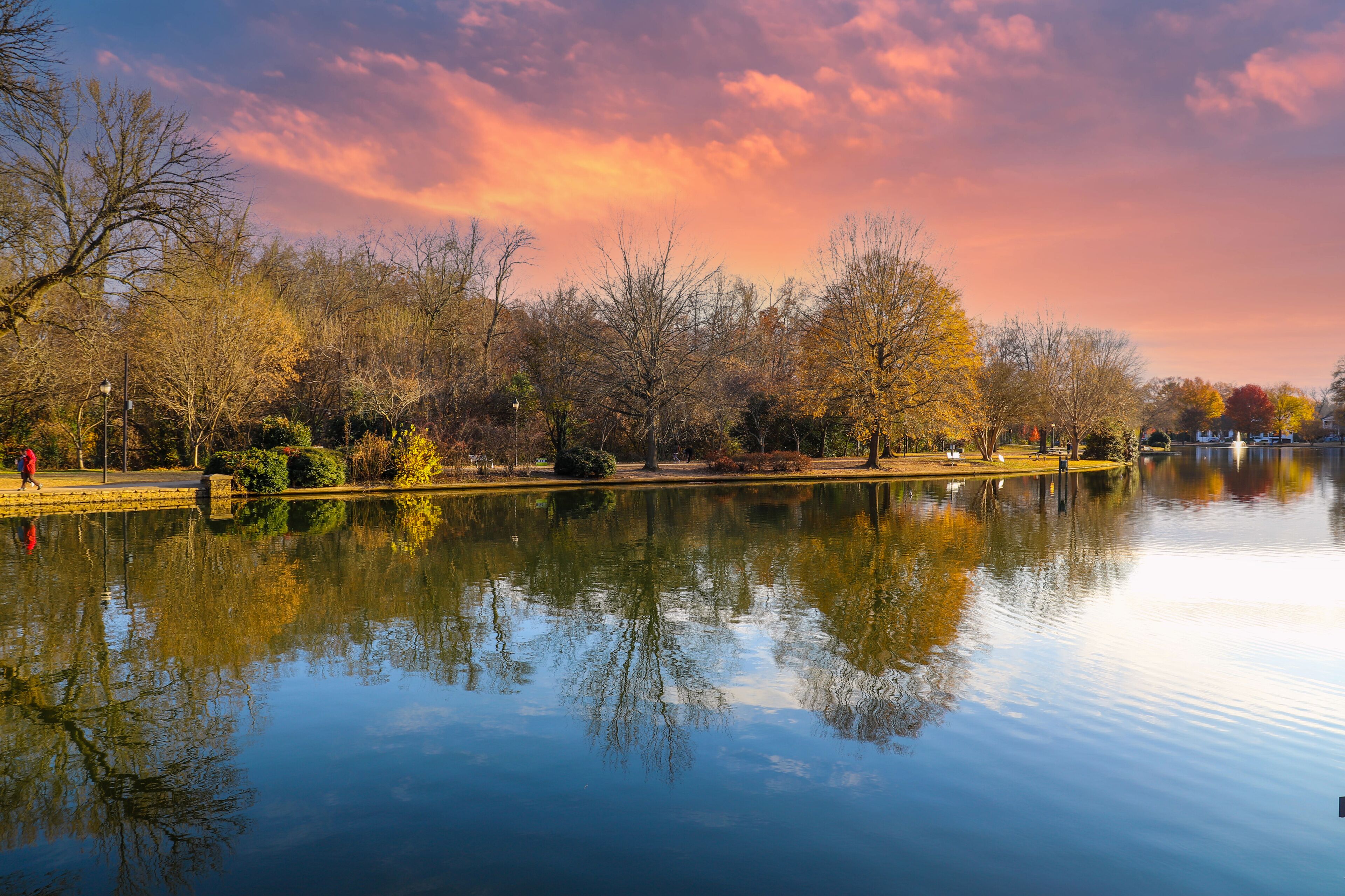 a stunning shot of a still lake in the park surrounded by gorgeous autumn colored trees reflecting off the water at sunset at Freedom Park in Charlotte North Carolina USA