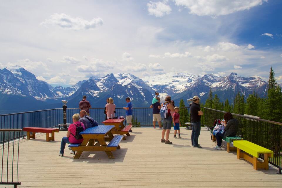 A wooden deck with picnic tables overlooking snow-capped mountains.