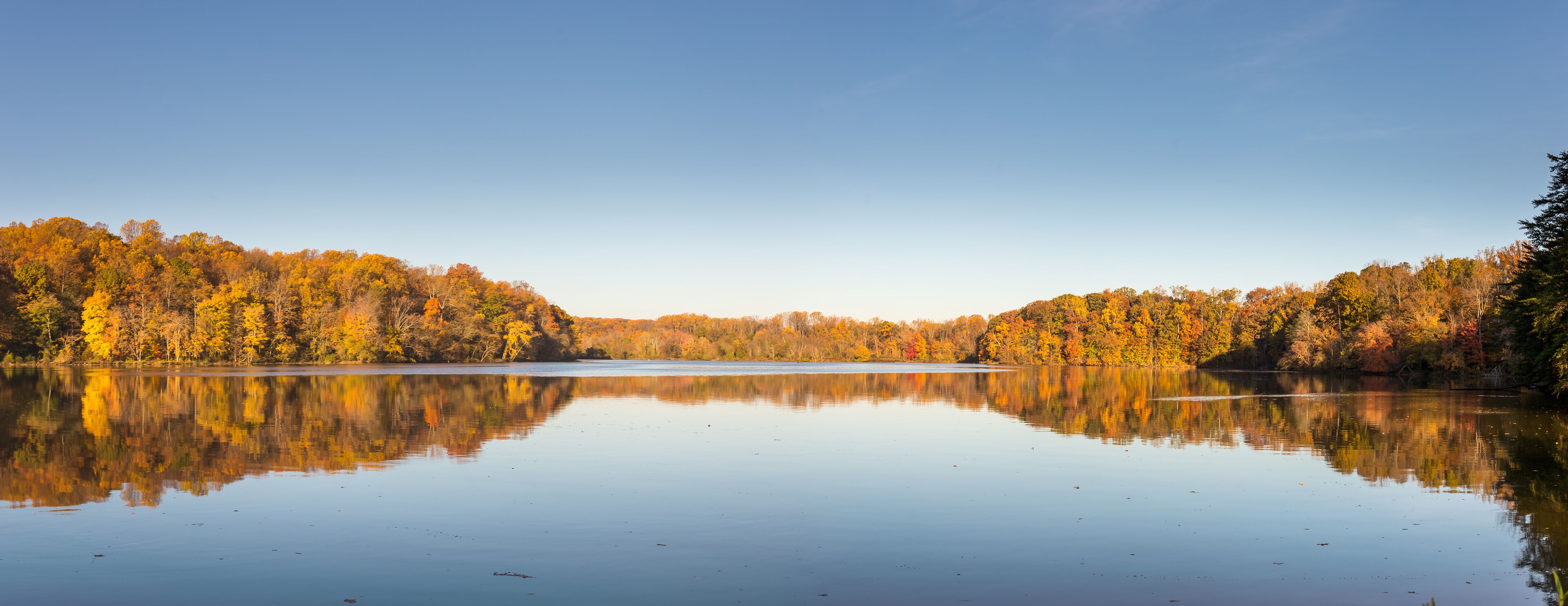 A calm lake surrounded by autumn-colored trees.