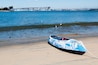 Glorietta Marina Park beach in Coronado, California, with a kayak in the foreground and the San Diego-Coronado Bay Bridge and San Diego Bay in the background.