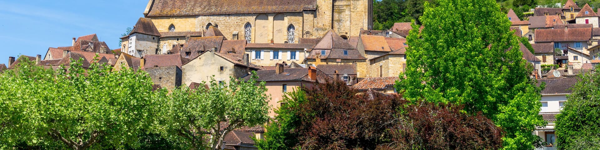 view of the historic village center of Saint-Cyprien with traditional brown stone houses and catholic church