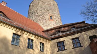A building with a stone tower and red-tiled roof.