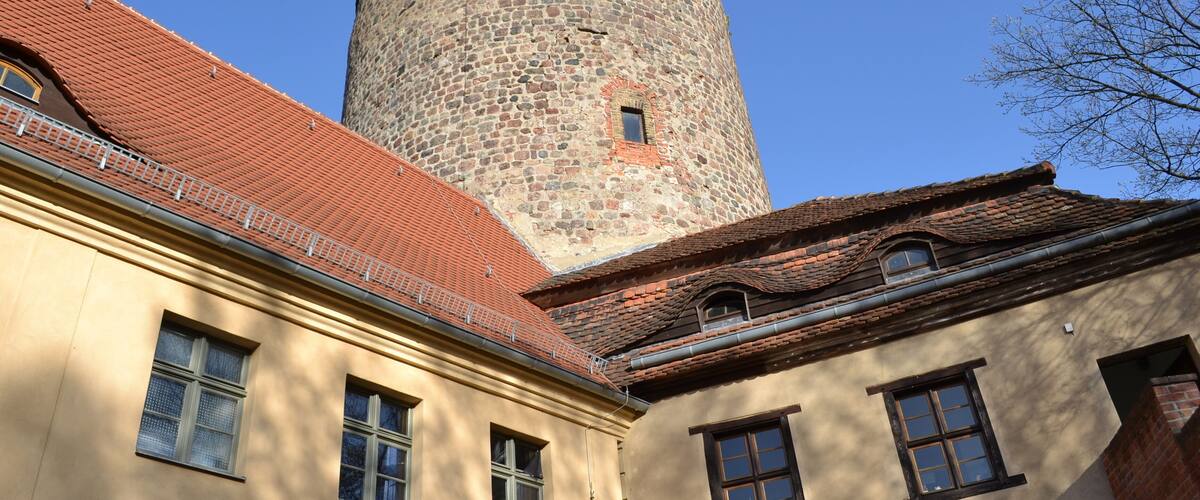 A building with a stone tower and red-tiled roof.