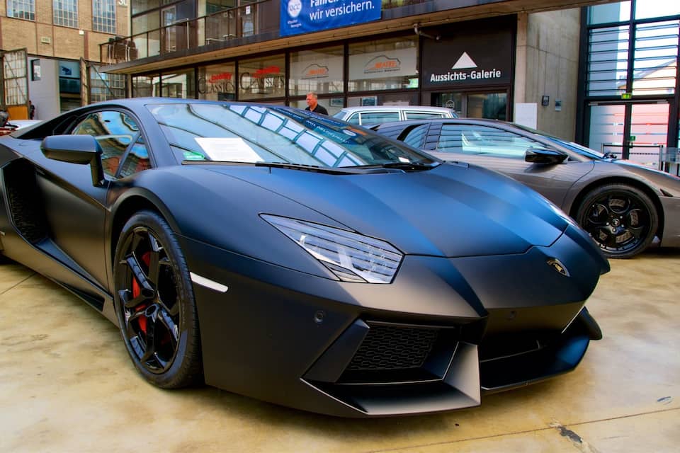 A black sports car parked in a showroom with other luxury cars.