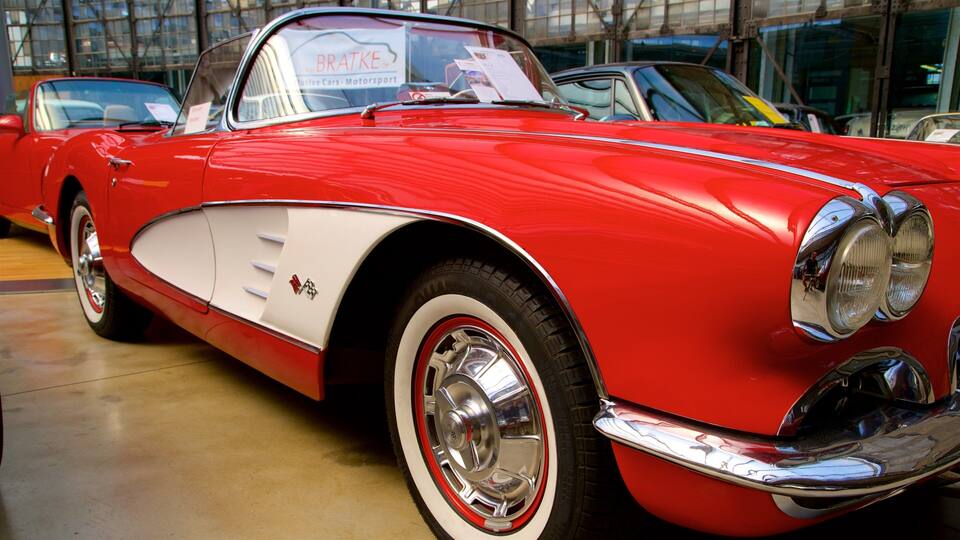 Un auto clásico rojo y blanco con detalles cromados y una patente visible.