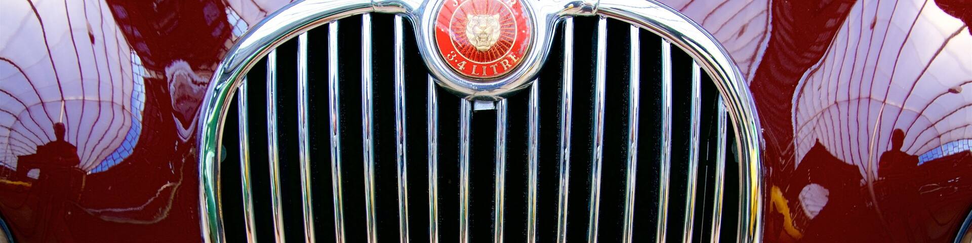 Parrilla de un coche clásico con el emblema de Jaguar y una luz roja.