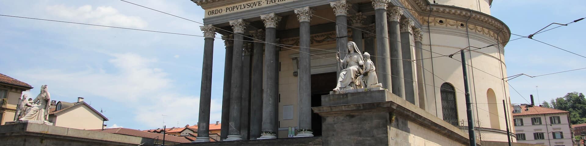 A classical building with columns and a dome, featuring inscriptions and statues.