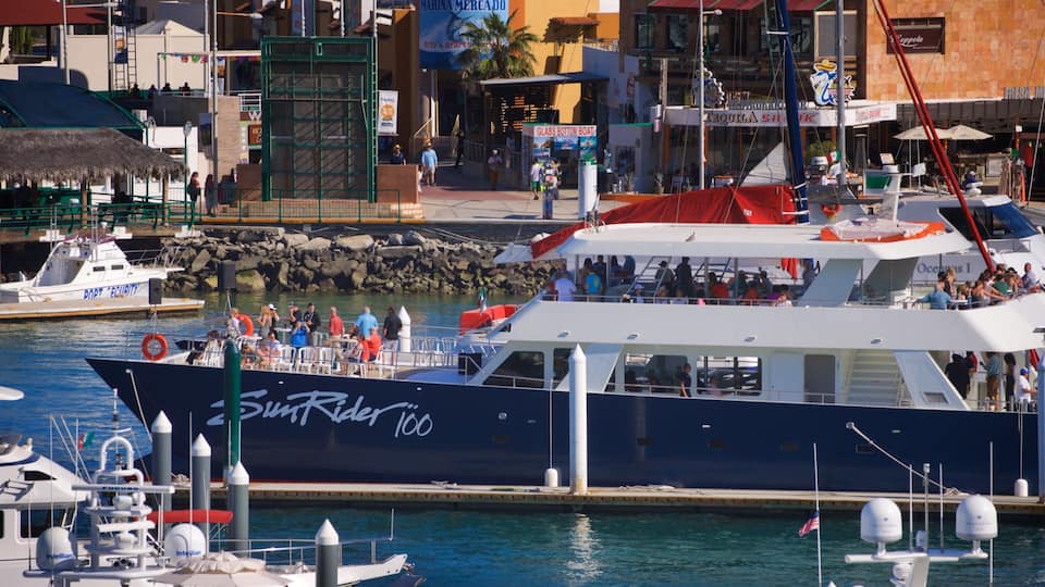 A large boat named 'SunRider 100' docked at a marina with a cityscape in the background.