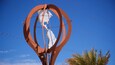 Eine Metallskulptur eines Globus mit rotem Rahmen vor blauem Himmel.