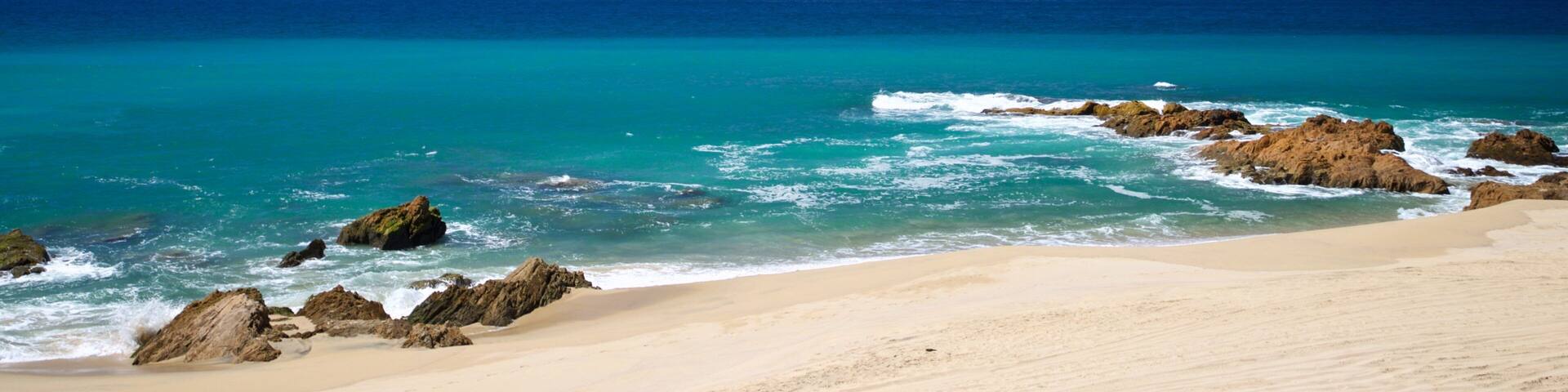 Migrino which includes a sandy beach, rocky coastline and general coastal views