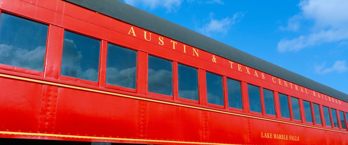 A red train with the number 699 and the words "Austin & Texas Central Railroad" and "Lake Marble Falls" on it.