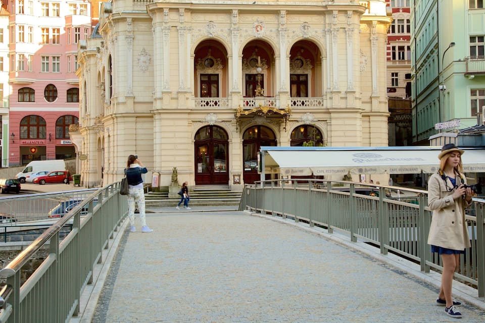 A historic building with ornate architecture, a pedestrian bridge, and a cafe restaurant.