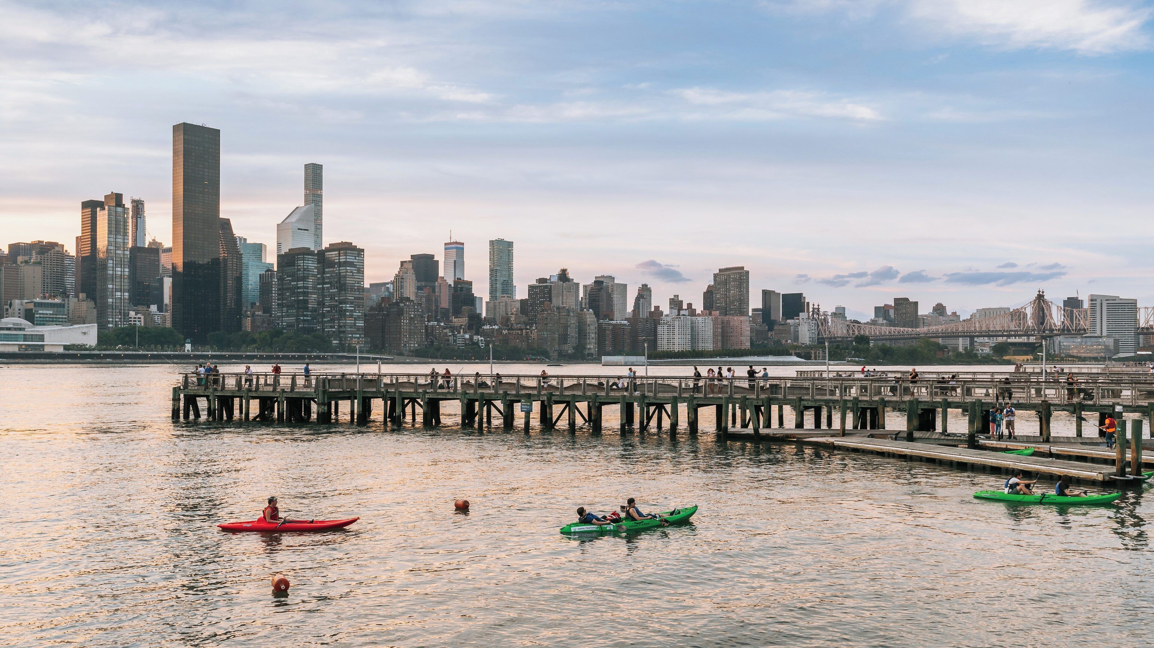 Kayakers enjoy a serene evening paddle at Gantry Plaza State Park, overlooking the skyline of Long Island City in New York City