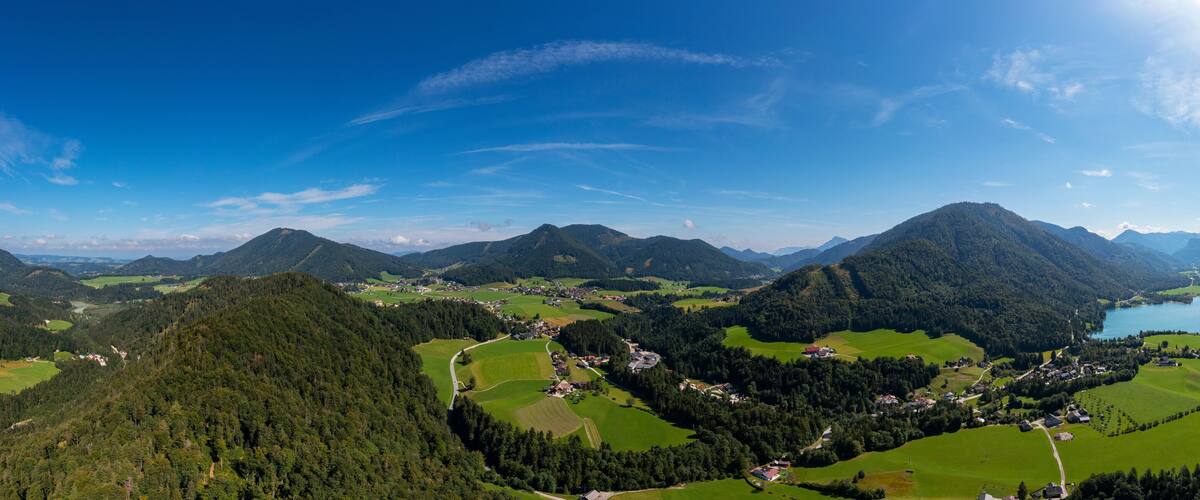 A mountainous landscape with a lake, green fields, and scattered houses.
