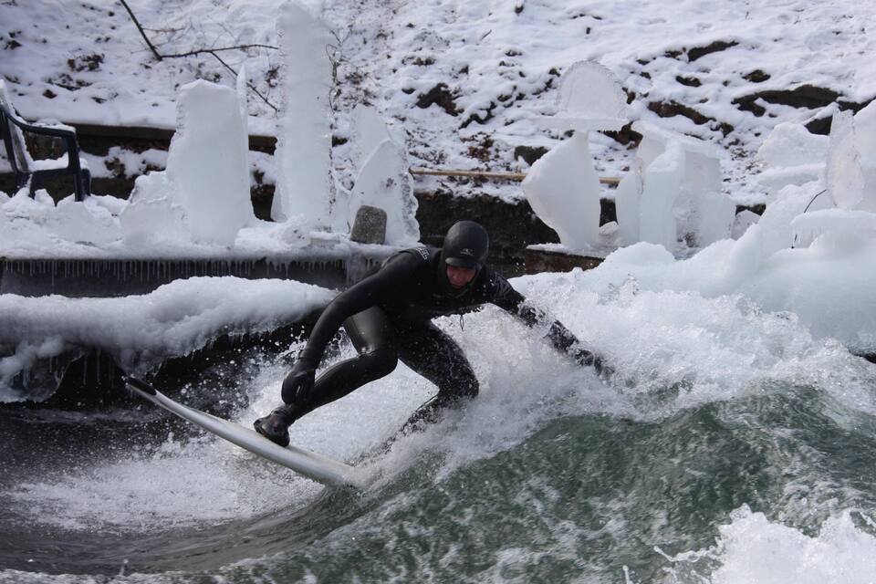 A person surfing on a wave in a snowy environment.