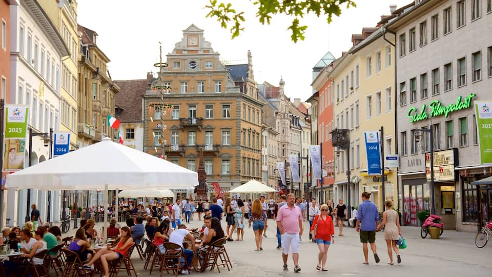 A bustling street with cafes, people walking, and historic buildings.