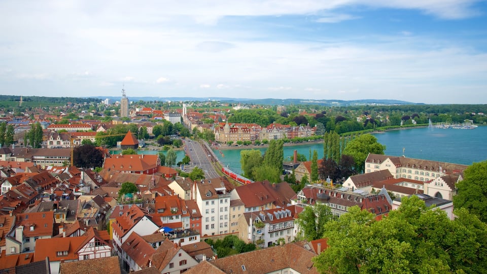 A riverside town with historic buildings, a bridge, and a distant tower.