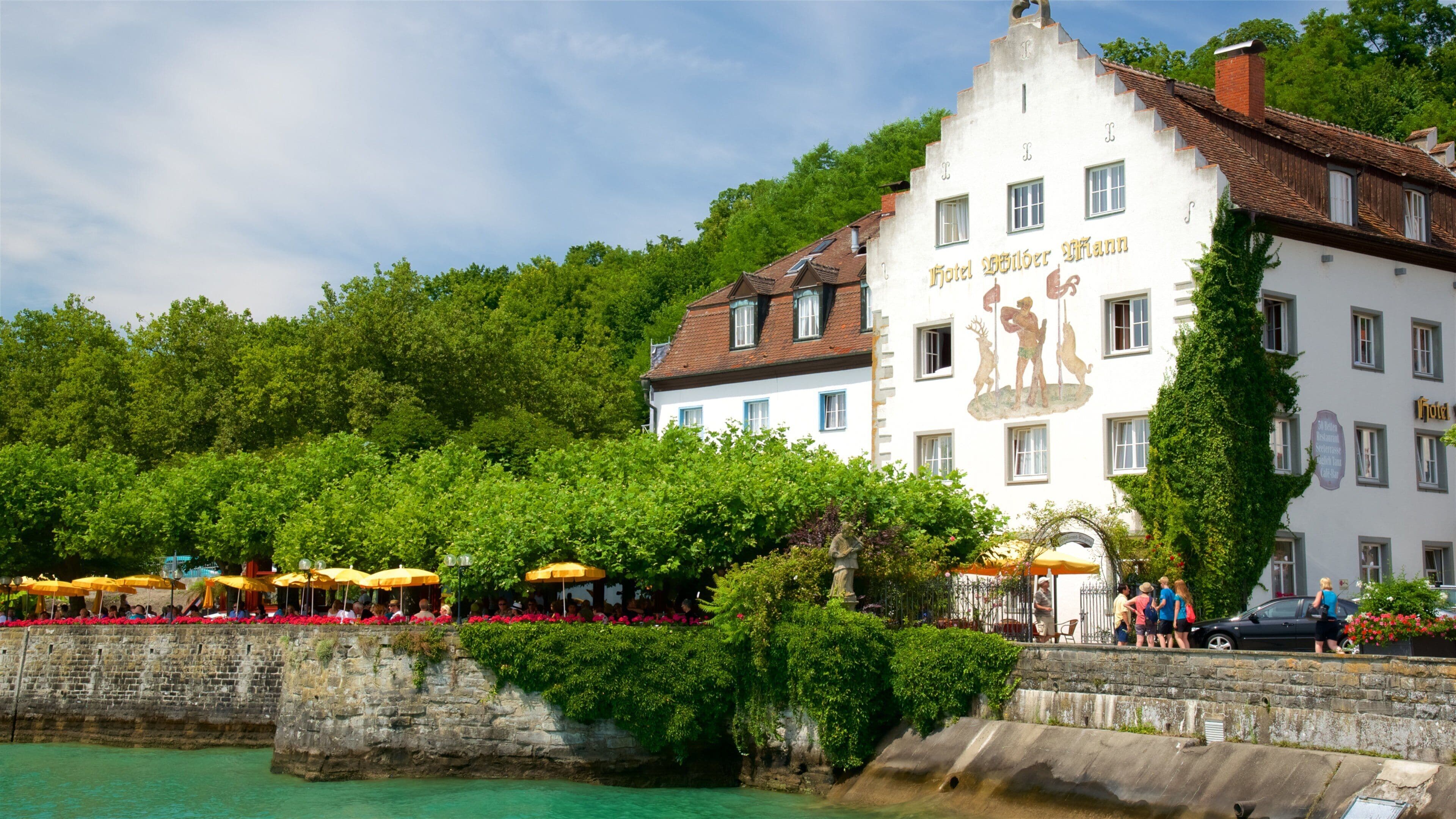 A waterfront building with outdoor seating and a mural.